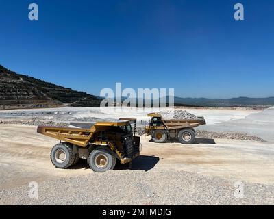 Dumper che lavorano in una cava di calcare. Trasportano il materiale al frantumatore. Foto Stock