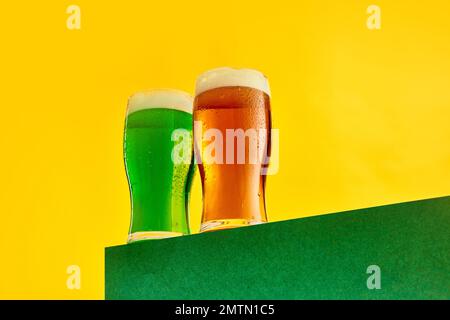 Due bicchieri di birra verde freddo e magra schiumosa su sfondo giallo. Celebrazione, festival. Concetto di celebrazione del giorno di san patrizio, birreria Foto Stock