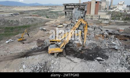 Escavatori con martello idraulico che demoliscono un edificio industriale. Foto Stock