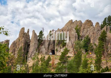 Un ingresso per un veicolo stretto attraverso una grotta rocciosa lungo l'autostrada di Needles in un paesaggio estivo del South Dakota Foto Stock