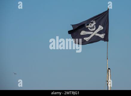 jolly roger. Pirata flag.contro lo sfondo del cielo blu. Foto Stock