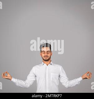 Concetto Zen. Calma uomo d'affari arabo meditando su sfondo grigio Foto Stock