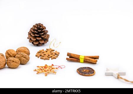 Decorazione di Natale con noci, stelle di legno e coni di pino ritagliati su sfondo bianco come studio shot Foto Stock