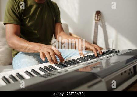 Mani di un uomo di talento che suona il sintetizzatore quando lavora a una nuova canzone Foto Stock