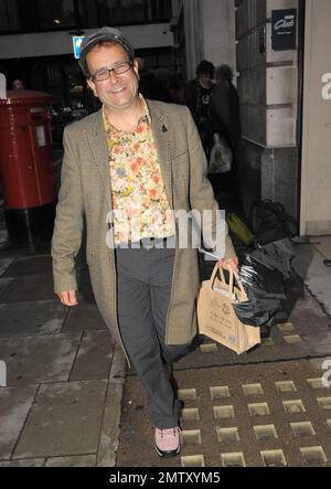 '80s e '90s il presentatore televisivo per bambini Timmy Mallett sorride mentre lascia la BBC radio 2 indossando un outfit in contrasto composto da una camicia floreale arancione e gialla con motivi floreali, pantaloni a righe e scarpe rosa. Londra, Regno Unito. 11/5/10. Foto Stock