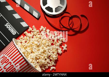 Composizione piatta con delizioso popcorn su sfondo rosso Foto Stock