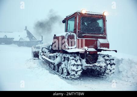 Il trattore pulisce la strada in caso di nevicate. Stagione invernale Foto Stock