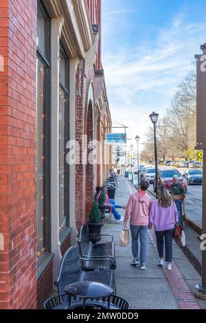 WAXHAW, NC, USA-28 GEN 2023: Vista lungo il marciapiede di South Main St Giovane coppia a piedi, altre persone sedute. Immagine verticale. Foto Stock