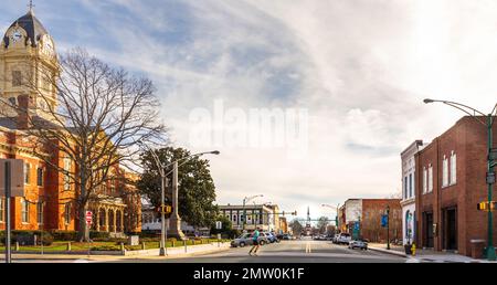 MONROE, NC, USA-28 GEN 2023: Vista grandangolare lungo Main Street, oltre il tribunale, verso la prima chiesa Battista. Giornata invernale soleggiata. Passaggio di corridori Foto Stock