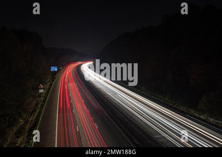 Sentieri leggeri lasciati dal traffico in velocità che attraversa la notte sull'autostrada M40 nel Regno Unito. Foto a bassa velocità dell'otturatore e a lunga esposizione. Foto Stock