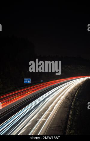 Sentieri leggeri lasciati dal traffico in velocità che attraversa la notte sull'autostrada M40 nel Regno Unito. Foto a bassa velocità dell'otturatore e a lunga esposizione. Foto Stock