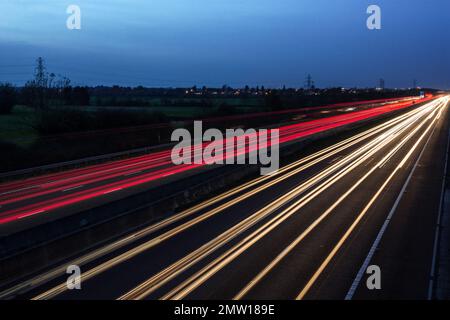 Sentieri leggeri lasciati dal traffico in velocità che attraversa la notte sull'autostrada M40 nel Regno Unito. Foto a bassa velocità dell'otturatore e a lunga esposizione. Foto Stock