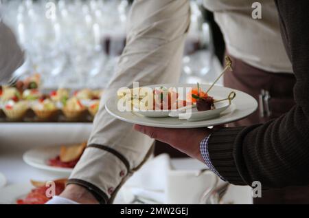 Mano dell'uomo con un piatto di antipasti al tavolo da pranzo Foto Stock