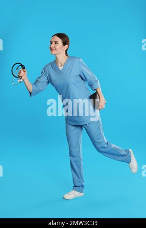 Medico con appunti e stetoscopio in esecuzione su sfondo blu Foto Stock