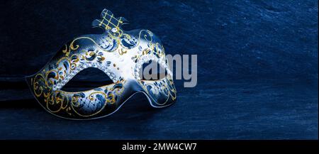 Festosa maschera di carnevale veneziana con decorazioni in oro glitter e perle di diamante su sfondo blu scuro. Foto Stock
