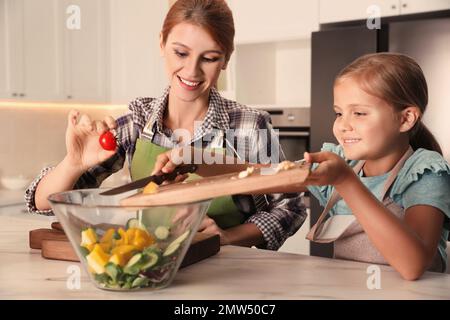 Madre e figlia cucinano l'insalata insieme in cucina Foto Stock