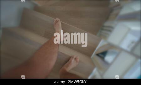 Persone gambe POV scendendo le scale. Primo piano uomo piedi a piedi a casa. Punto di vista della persona nelle scale Foto Stock