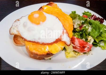 Croque Madame, prosciutto francese e formaggio piatto su pane al burro con uova in cima. Foto Stock