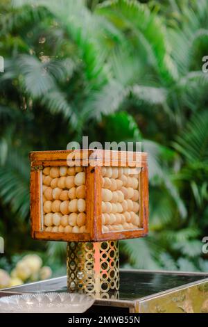 Un primo piano di una lampada in legno per esterni con base dorata nel cortile Foto Stock