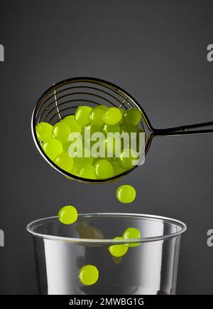palle di tè verde bolla di gelatina e tazza di plastica su sfondo nero scuro Foto Stock