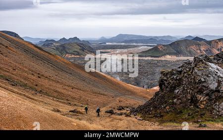 Due escursionisti sul Laugavegur, paesaggio vicino Landmannalaugar, paesaggio vulcanico drammatico, paesaggio di erosione colorata con montagne, campo di Lava Foto Stock