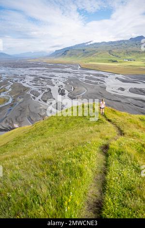 Escursionista su una collina, vista su terra alluvionale e paesaggio fluviale, meandri fluviali, Dimonarhellir, Suourland, Islanda Foto Stock