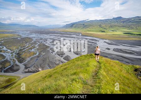 Escursionista su una collina, vista su terra alluvionale e paesaggio fluviale, meandri fluviali, Dimonarhellir, Suourland, Islanda Foto Stock