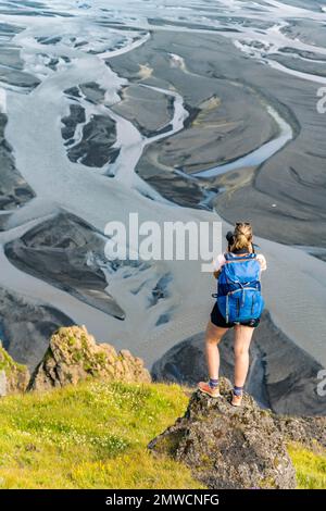 Escursionista su una collina, vista su terra alluvionale e paesaggio fluviale, meandri fluviali, Dimonarhellir, Suourland, Islanda Foto Stock