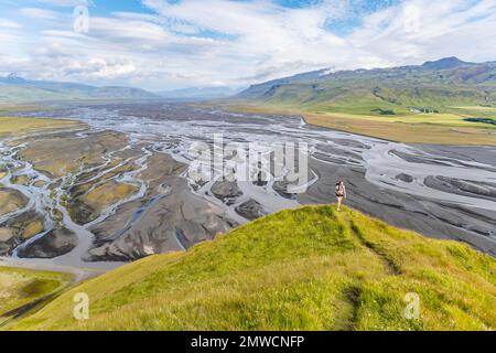 Escursionista su una collina, vista su terra alluvionale e paesaggio fluviale, meandri fluviali, Dimonarhellir, Suourland, Islanda Foto Stock