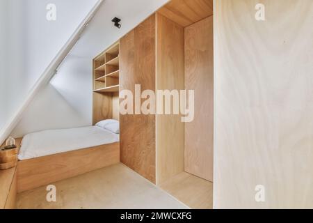 una camera da letto mansardata con pareti in legno e pareti bianche, vi è un piccolo letto nella camera ha costruito nella parete Foto Stock