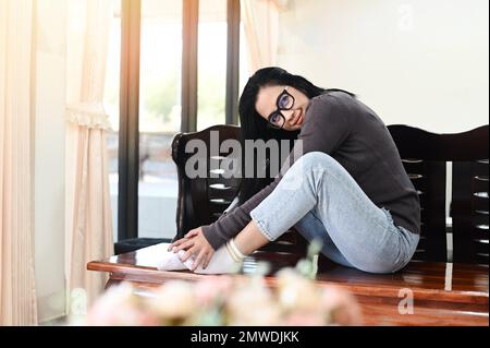 donna che si rilassa a casa, donna felice seduta appoggiata sul divano di legno femmina godere pigro week-end o vacanza, ragazza donna che si rilassa si sente prendere un riposo a casa Foto Stock