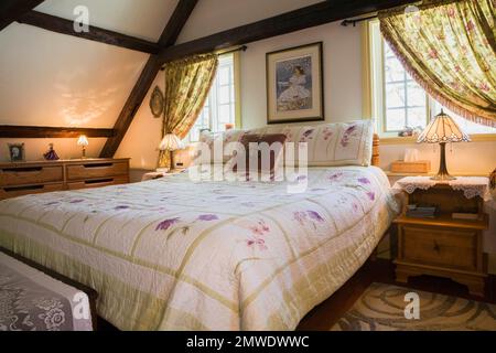 Letto king size nella camera da letto principale al piano superiore all'interno di una vecchia casa in stile cottage canadese del 1886 ricostruita. Foto Stock