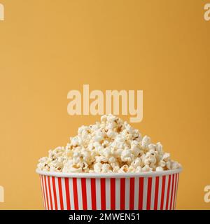 Delizioso popcorn in secchio di carta su sfondo giallo, primo piano Foto Stock