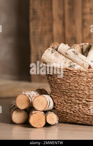 Cesto di vimini con legna tagliata a legna sul pavimento interno Foto Stock