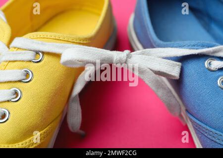 Scarpe legate insieme su sfondo rosa, primo piano. Fool's Day di aprile Foto Stock