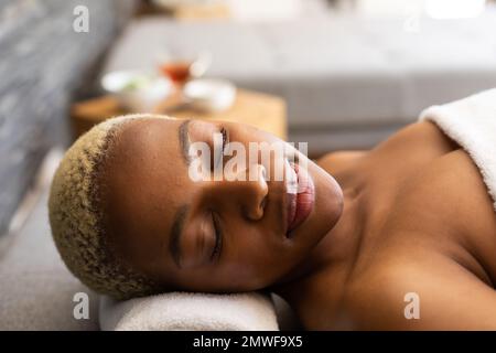 Donna afro-americana felice sdraiata su un asciugamano con gli occhi chiusi Foto Stock