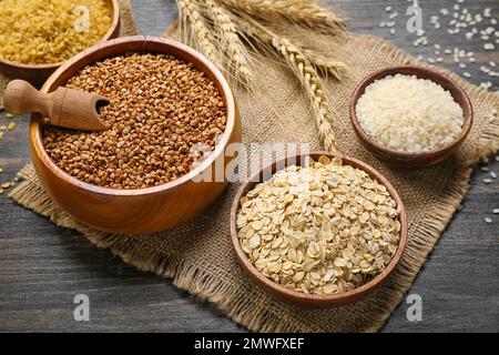 Ciotole di cereali diversi su fondo di legno scuro Foto Stock