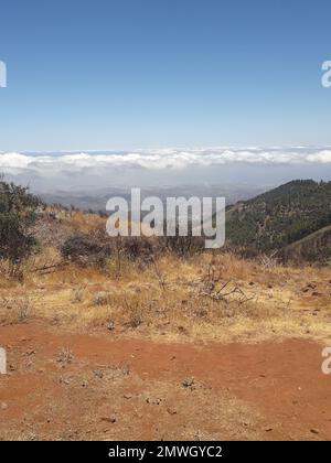 Uno scatto verticale delle nuvole sopra le montagne e sotto il cielo blu in una giornata di sole Foto Stock