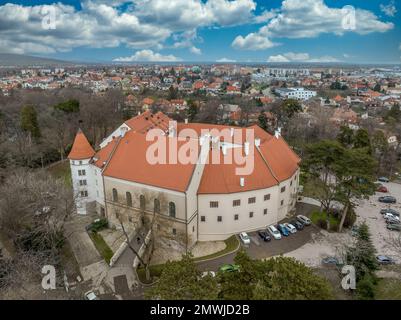 Veduta aerea del castello medievale di Pezinok (Bazin) con tetto rosso restaurato e centro medievale di commercio del vino con chiesa gotica e tracce di mura della città Foto Stock
