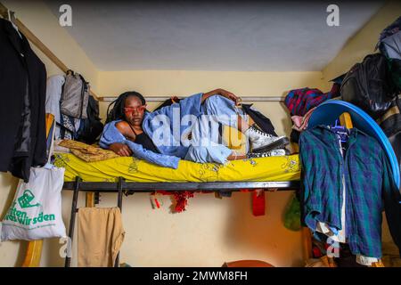 Cynthia Gesare di 20 anni posa sul suo letto all'interno della sua piccola stanza circondata da armadi a Kibera. I giovani kenioti sono spinti in una competenza di avere le proprie case lontano dai genitori, dove soprattutto imparano ad affrontare la vita attraverso diverse sfide. La competizione di avere le camere meglio decorate piene di diversi abiti di design è un modo per tenere lontano dalle sfide quotidiane della vita, come l'abuso di droghe, le gravidanze adolescenziali matrimoni precoci, e giudizi negativi da parte della gente del posto. Per la maggior parte dei giovani avere una casa è l'inizio di una nuova vita e. Foto Stock