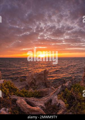 Uno scatto verticale di un tramonto ipnotico all'orizzonte sul mare Foto Stock