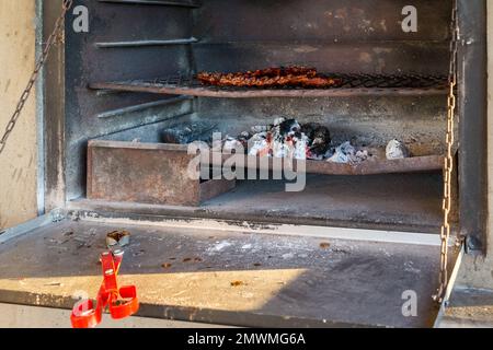 Costolette di maiale, carne, cibo su una griglia di metallo in un camino sopra carbone in fiamme e il concetto di legno braai Heritage Day in Sudafrica Foto Stock
