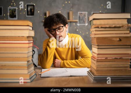 Studenti che leggono libri preparandosi per gli esami, stanco giovane addormentato al tavolo. Spazio di copia Foto Stock