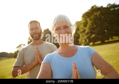 Rimanere giovani a cuore attraverso lo yoga. Ritratto di una coppia matura felice che fa yoga insieme all'aperto. Foto Stock