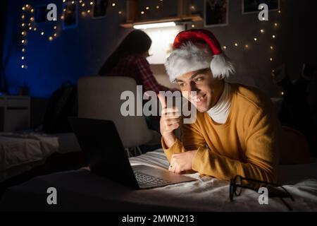 Giovane uomo che lavora a casa il giorno di natale utilizzando un computer portatile di notte. Spazio di copia Foto Stock