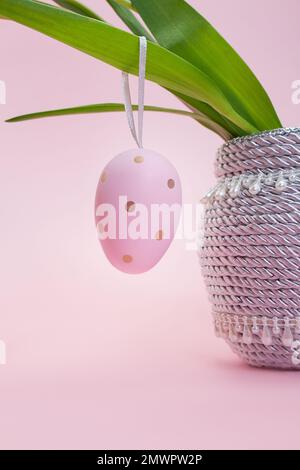 L'uovo di colore rosa pende sulle foglie. Bouquet in vaso. Pasqua. Spazio di copia Foto Stock