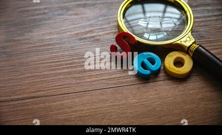 Concetto di ottimizzazione dei motori di ricerca. Lente d'ingrandimento e alfabeto di seo su uno sfondo di legno. Foto Stock