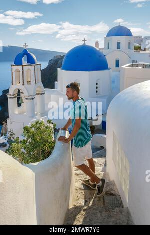 I giovani turisti visitano Oia Santorini Grecia in una giornata di sole durante l'estate con case e chiese imbiancate, l'isola greca Cicladi del Mar Egeo Foto Stock