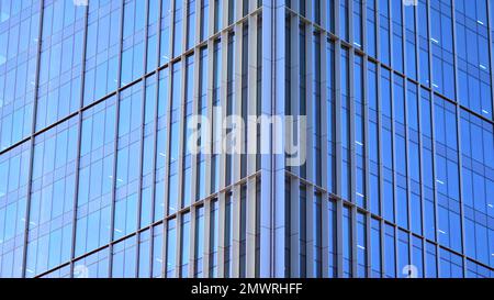 Edificio in vetro con facciata trasparente dell'edificio e cielo blu. Parete strutturale in vetro che riflette il cielo blu. Frammento astratto di architettura moderna. Foto Stock