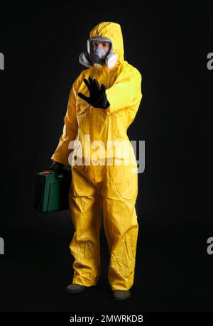 Uomo in tuta protettiva chimica su sfondo nero. Ricerca sui virus Foto Stock